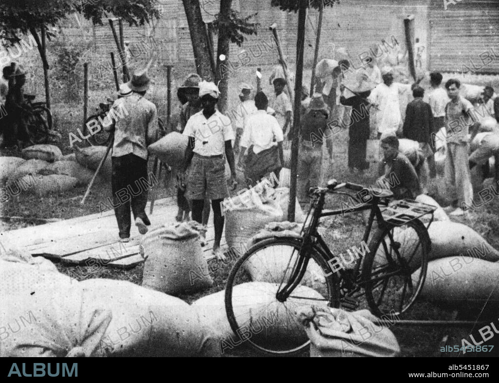 Malaya British Pursues "Scorched Earth" Policy - Pursuing in "Scorched Earth" policy, the British Forces in Malaya have burnt thousands of bales of rubber, destroyed rubber factories, and smashed Machinery.Scene at Seremban, about 35 miles South of Kuala Lumpur, when bags of rice were handed out to Chinese who carried it away. February 1, 1942.