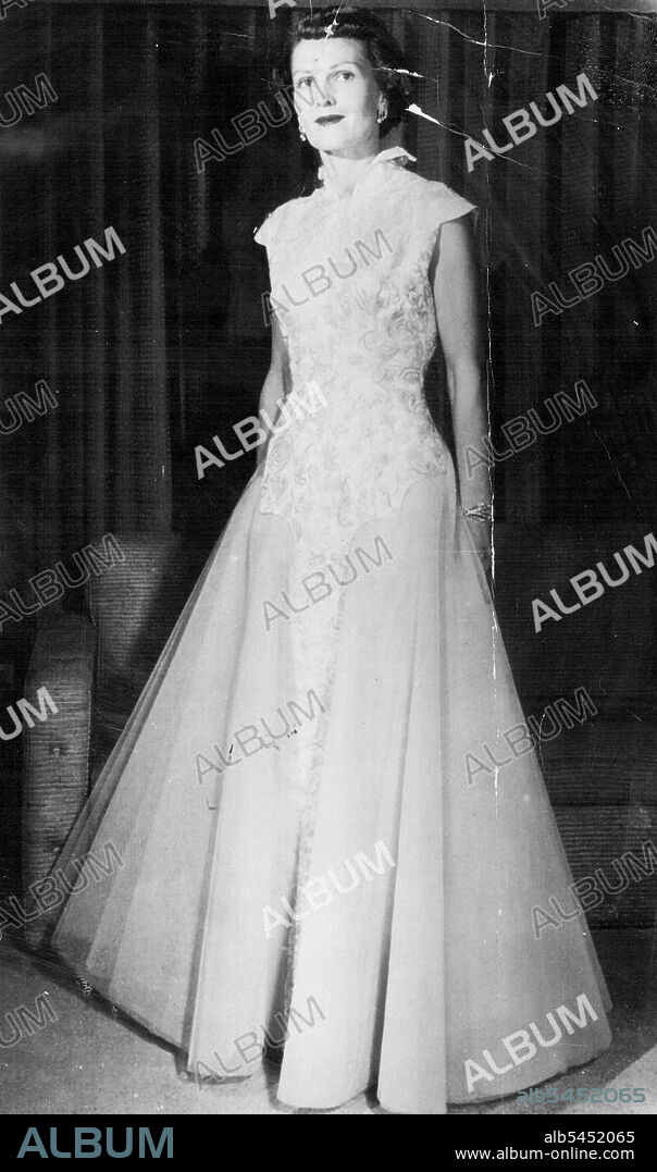 Displays Inaugural Gown -- Mrs. Richard Nixon, wife of the Vice President-elect, poses at home today in the gown she will wear at the inaugural ball next Tuesday evening. The skirt is of soft blue-green net. The fitted bodice of brocade has small patterned flowers outlined in seed pearls, centered with rhinestones, and stemmed with crystal bugle beads. The gown has a high, standing collar. January 14, 1953. (Photo by AP Wirephoto).