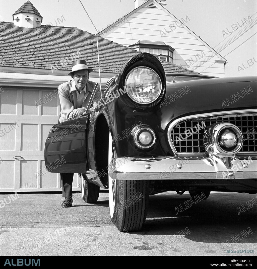Circa 1955, Hollywood, California, USA: American actor and Hollywood icon FRANK SINATRA poses with his 1955 'T-bird' Ford Thunderbird convertible sports car for a 1950's Ford Thunderbird Ad campaign.