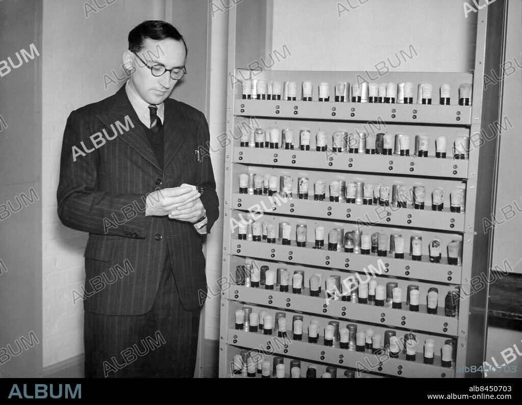 Orig. bildtext... BRITISH EDSAC WILL SURPASS AMERICAN ENIAC A new British invention, the electronic delay storage automatic calculator (EDSAC) is now in the process of a 33-year-old director of Cambridge Mathematical laboratory. This new brain will have 25 times more knowledge than its American counterpart, Eniac, and is composed of some thousand valves, 32 4ft. mercury tubes, and gives the answers to such problems as 500 ten-figure numbers, or 1,000 five-figure numbers, and of research into engineering, astronomy and athom physics, and other problems too complicated for the human brain. 100,000 diff. calculations can be completed per minute. The picture shows Dr. H.V. Wilkes with some of the thousand valves. Anm. Maurice Vincent Wilkes, f. 1913, brittisk datavetenskapsman, professor i Cambridge 1946-80. Glasögon Kostymer Radiorör CD283 persons: MAURICE WILKES sites: CAMBRIDGE;STORBRITANNIEN.