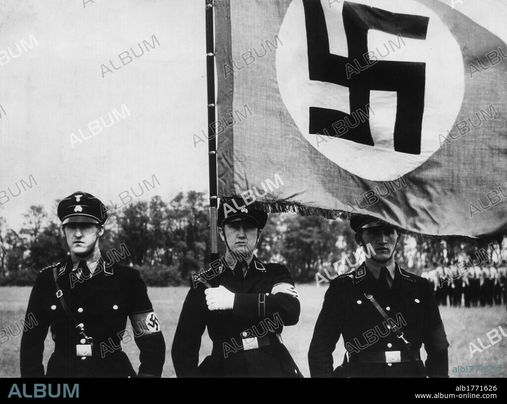 A parade of SS. Three members of the German SS with the Nazi flag at a military parade in Munich. Munich, 1926.