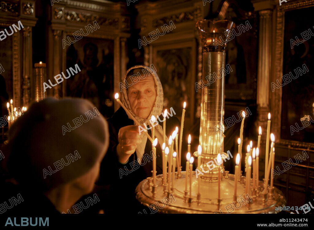 Russian Orthodox worshipper lighting candles in church in Zagorsk, near Moscow, Russia.