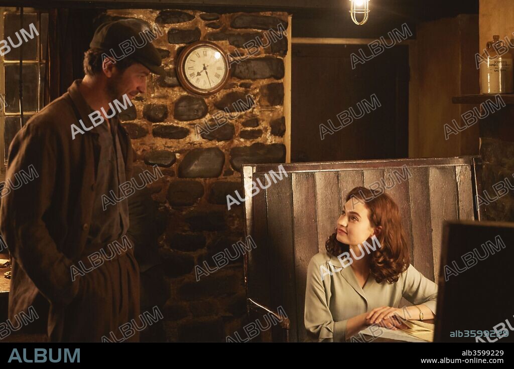 LILY JAMES and MICHIEL HUISMAN in GUERNSEY, 2018 (THE GUERNSEY LITERARY AND POTATO PEEL PIE SOCIETY), directed by MIKE NEWELL. Copyright BLUEPRINT PICTURES.