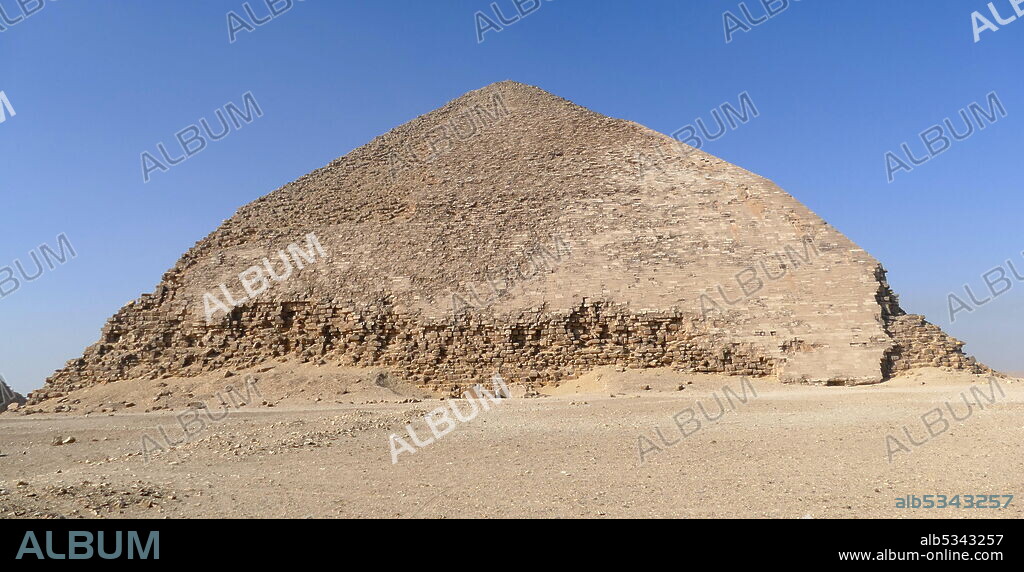 The Bent Pyramid is an ancient Egyptian pyramid located at the royal necropolis of Dahshur, approximately 40 kilometres south of Cairo, built under the Old Kingdom Pharaoh Sneferu (c. 2600 BC). A unique example of early pyramid development in Egypt, this was the second pyramid built by Sneferu. The Bent Pyramid rises from the desert at a 54-degree inclination, but the top section (above 47 meters) is built at the shallower angle of 43 degrees, lending the pyramid its very obvious 'bent' appearance..