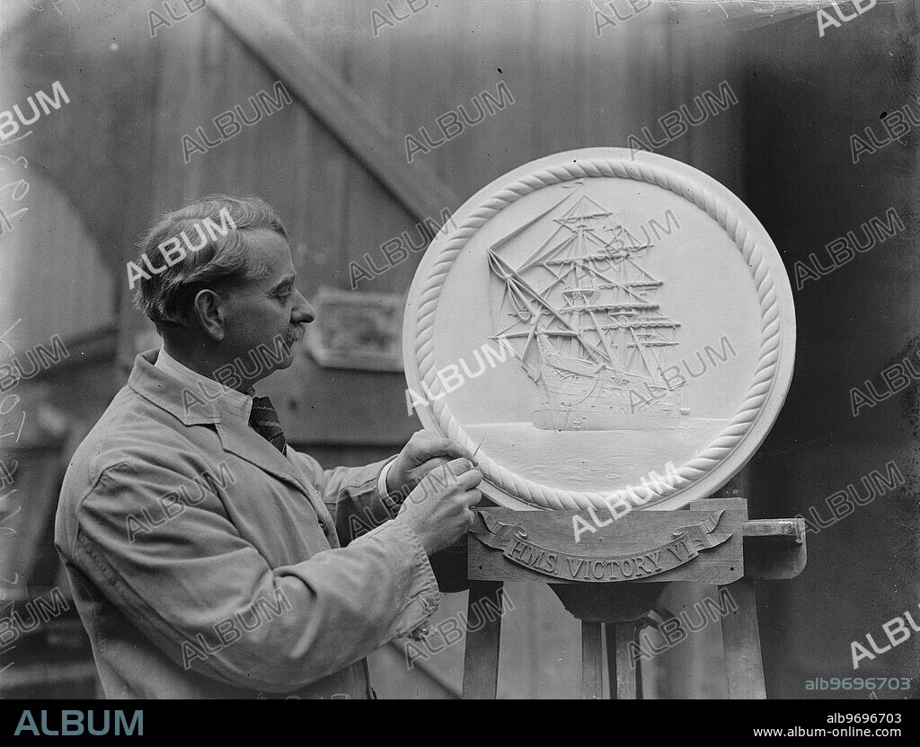 Prince of Wales to unveil RNVR commemoration trophy at the Crystal Palace . Mr Hawkins at work in his London studio on the large plaque showing HMS Victory , which will form part of the trophy . 11 March 1931.