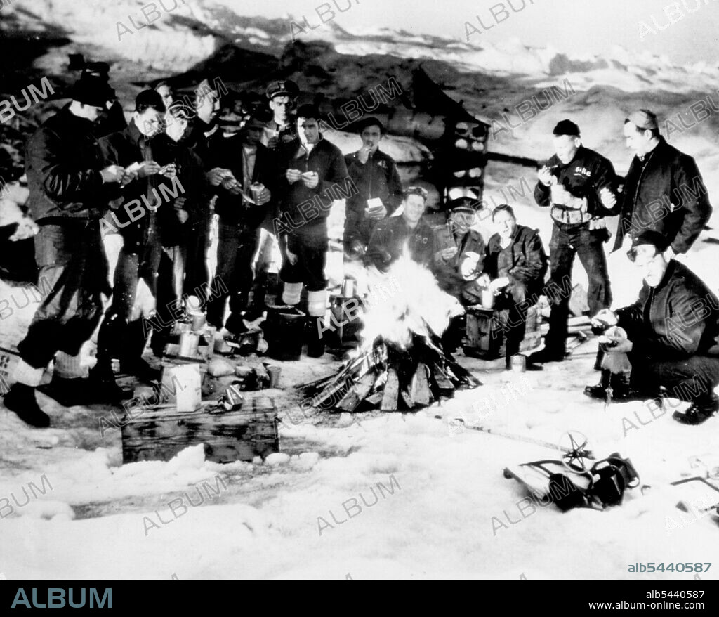 Yanks Dine On Enemy Food In Greenland -- Coast Guardsmen eat German canned food found near a deserted enemy vessel off Greenland recently. From Left, foreground, are: Sheppard Morris, Bronx, New York City: Irwin Wasserman, Brooklyn, N. Y.: Joseph Soroko, Ruth Erford, N.J.; Alphonse Szumiel, Buffalo, N.Y.; eugene J. Deberardinis, Martin's Greek, PA.: Albert W. Sawler, Avon, Mass.: Donald Mixon, Bogalusa, LA.: LT. F.H. Harmon, N. Quincy, Mass.: Wayne C. So wers, Gardners, PA.; James Mountain, Alt.