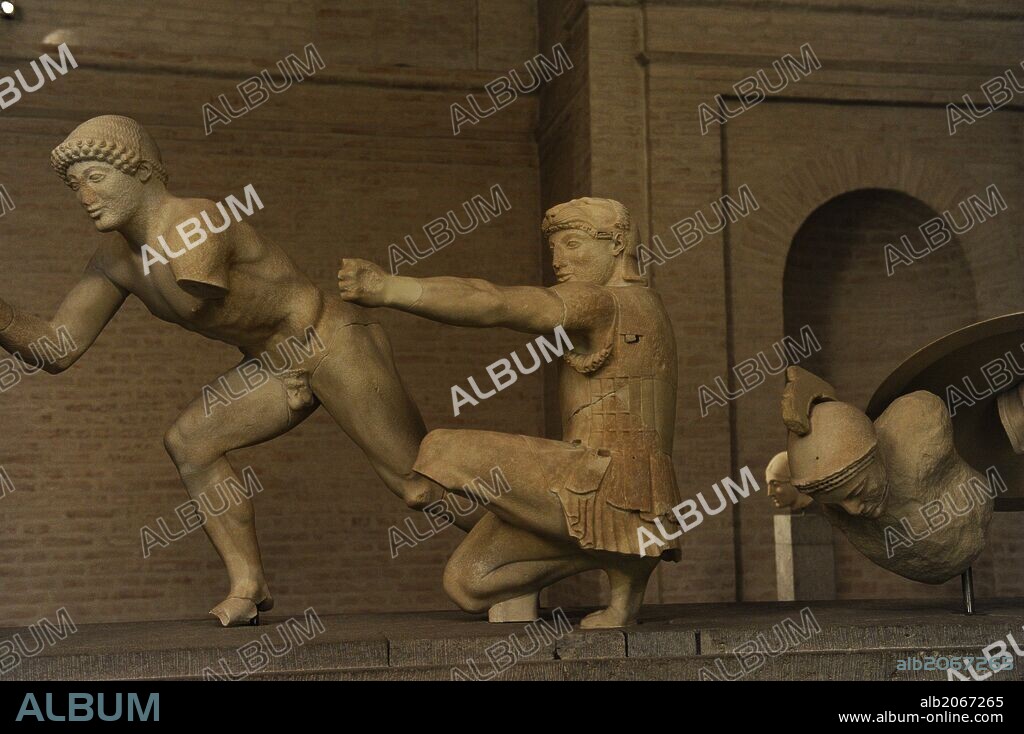 ARTE GRIEGO. GRECIA. Grupo escultórico del Frontón Este del templo de Egina. Alrededor de 480 aC. Dos figuras que representan guerreros (griegos) en la Guerra de Troya. El ayudante del guerrero, y el arquero arrodillado, con piel de león, como Heracles / Hercules y un soldado troyano herido. Glyptothek. Munich. Alemania. Europa.