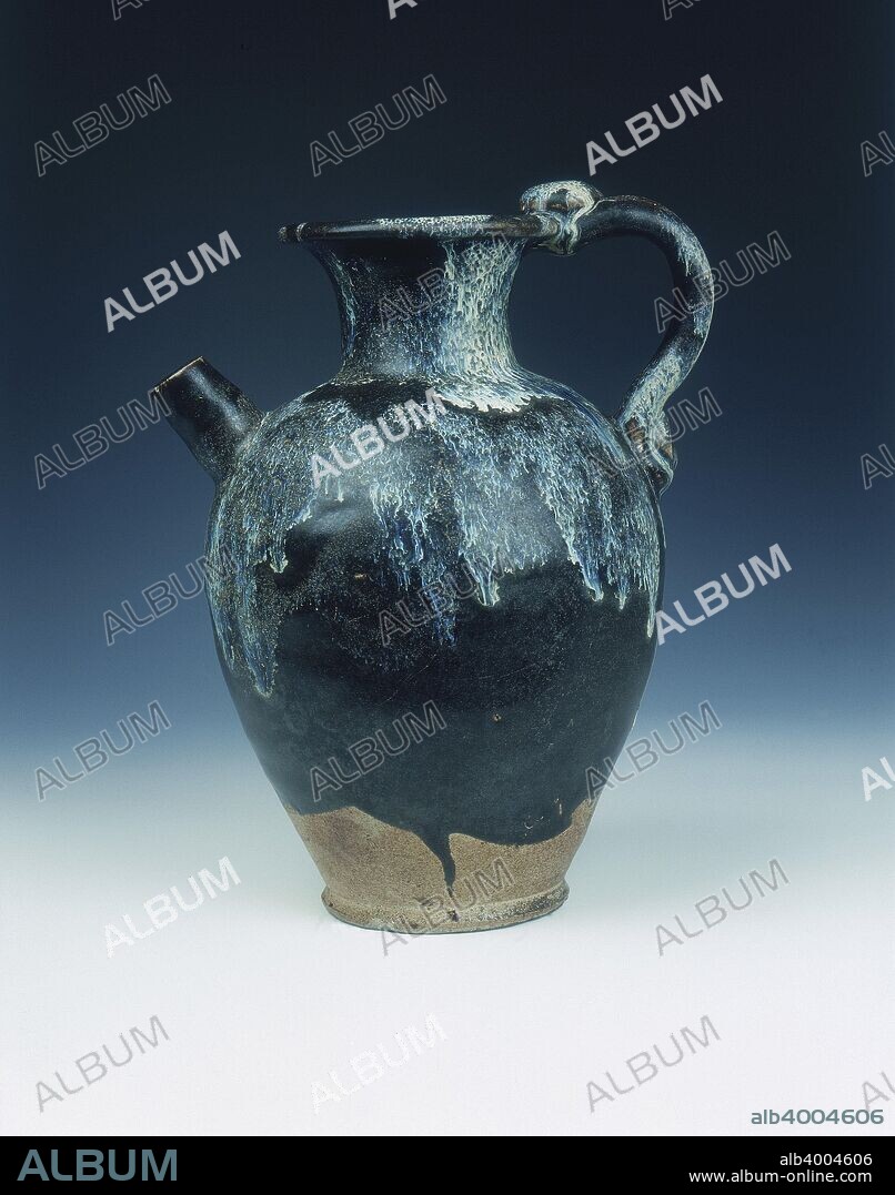 Black glazed ewer with blue phosphatic suffusions, Tang dynasty, China, 8th-9th century. A stoneware huangdao type ewer with a short circular spout and double strap studded handle inspired by a leather original. The ewer is covered with a thick, black glaze with extensive pale bluish phosphatic suffusions, the lower portion and base are unglazed showing the greyish brown body and solid knife-parred foot.