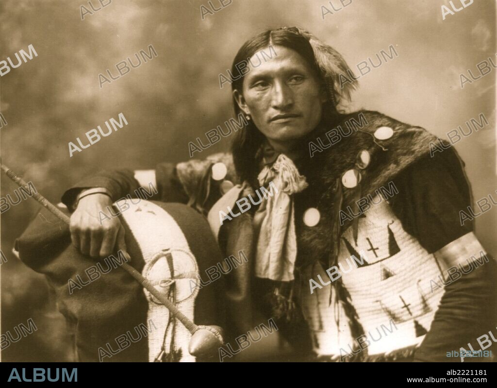 Eddie Plenty Holes, a Sioux Indian, half-length portrait, facing front, holding tomahawk.