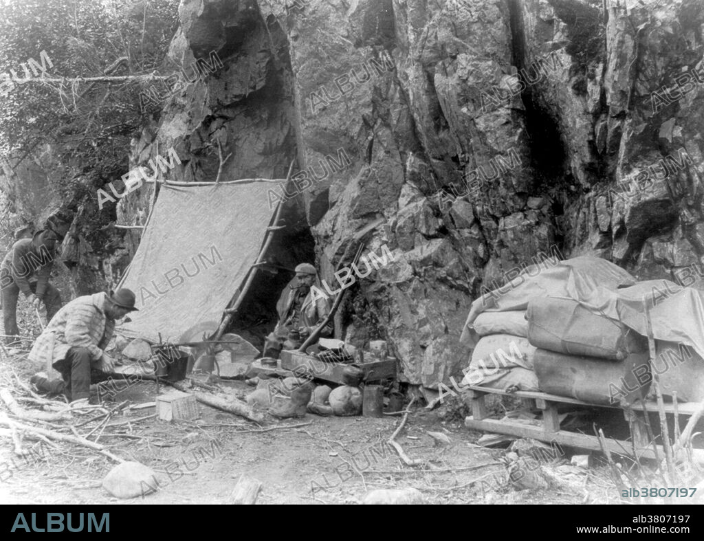 Packer's home, foot of canyon, Dyea Trail. The Klondike Gold Rush was a migration by an estimated 100,000 prospectors to the Klondike region of the Yukon between 1896-99. Gold was discovered by local miners on August 16, 1896 and, when news reached Seattle and San Francisco, it triggered a stampede of would-be prospectors. To reach the gold fields most took the route through the ports of Dyea and Skagway in Alaska. Here, the Klondikers could follow either the Chilkoot or the White Pass trails to the Yukon River and sail down to the Klondike. Each of them was required to bring a year's supply of food by the Canadian authorities in order to prevent starvation. In all, their equipment weighed close to a ton, which for most had to be carried in stages by themselves. Together with mountainous terrain and cold climate this meant that those who persisted did not arrive until summer 1898. Mining was challenging as the ore was distributed in an uneven manner and digging was made slow by permafrost. In the summer of 1899, gold was discovered around Nome in west Alaska, and many prospectors left the Klondike for the new goldfields, marking the end of the rush. Gold mining activity lasted until 1903. Photo by LaRoche, 1897.