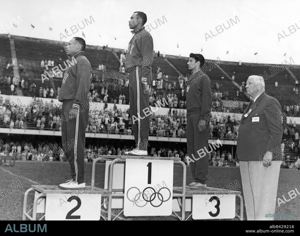 FINLAND HELSINGFORS 1952-07.. Tre herrar på prispallen efter finalen i längdhopp vid de olympiska sommarspelen 1952. Från vänster ses Meredith Gourdine (USA), silvermedaljör, Jerome Biffle (USA), guldmedaljör, och Ödön Földessy (Ungern), bronsmedaljör. Prisutdelare är SIgfrid Edström, svensk f.d. ordförande i IOK.. Foto: Olympia-Kuva / AB Text & Bilder / SVT / Kod: 5600. Mapp: Längdhopp I:286N. Prisutdelningar.