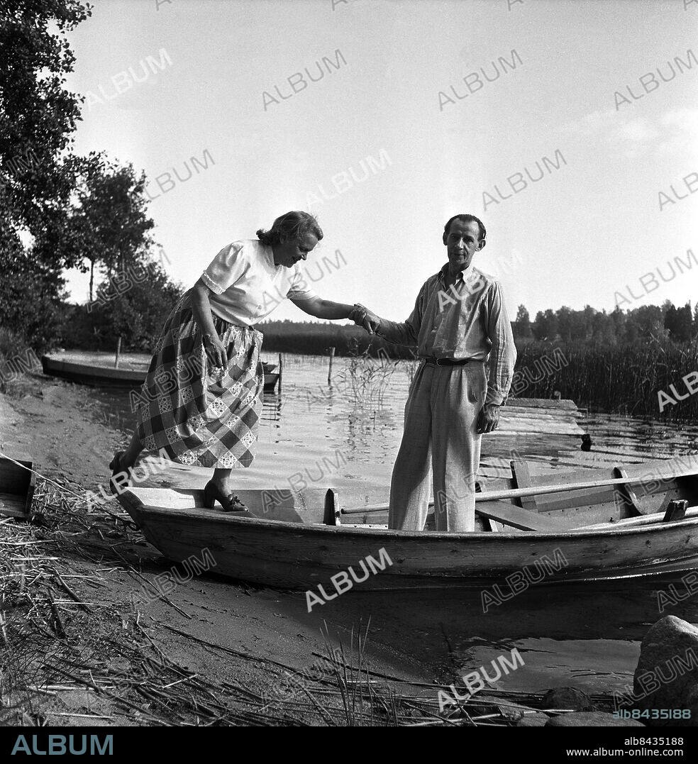 NORRBODA 1951 Författaren och poeten Nils Ferlin (1898-1961) hjälper sin fru Henny ombord i roddbåten i närheten av hemmet i Roslagen.. Foto: TT Historical / kod 1900.