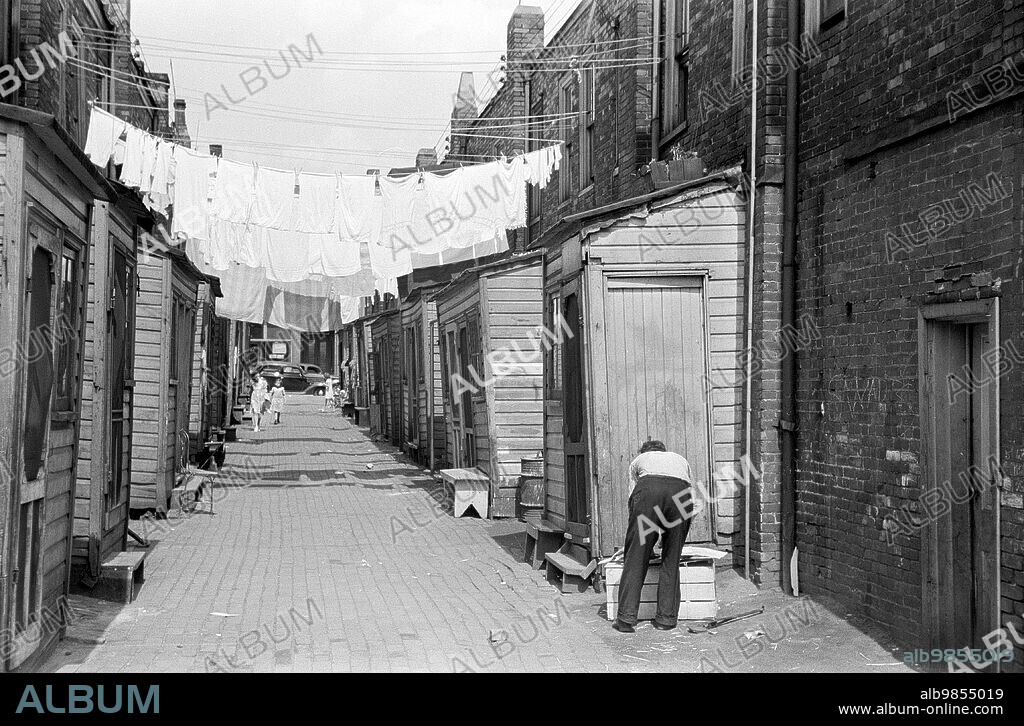 Narrow alley with hanging laundry, slum section, Ambridge, Pennsylvania, USA, Arthur Rothstein, U.S. Farm Security Administration, July 1938.