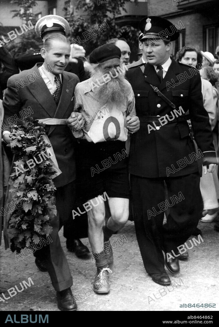 ©SCANPIX SWEDEN, 1951-07-07.. Cyklisten Gustaf Håkansson, kallad Stålfarfar.. Hyllas i mål efter att ha kört Sverigeloppet, Haparanda-Ystad. I mitten ser vi Stålfarfar, från Gantofta i Skåne med förre tävlingscyklisten Sture Andersson från Landskrona med lövkrans och överkonstapeln Ingvar Andersson. Stålfarfar har avverkat sträckan Haparanda- Ystad på 6,5 dygn. Han deltog utom tävlan, därav nollan på tröjan. Han körde nästan non-stop och var ett halvt dygn före de tävlande i mål.. Foto: Scanpix. Code: 20360.