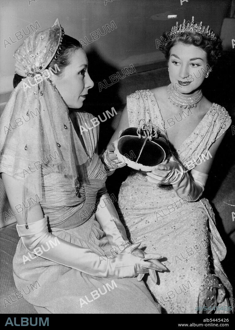Coronation Attire -- (Right) A court dress suitable for wear by Peeresses Beneath their Roses at the coronation of Queen Elizabeth II. The tiara is replaced by a coronet (or newly designed crimson velvet cap adorned with gold tassel as held in the model's hands) at the moments the Queen is crowned. At left is a head covering which conforms to the regulations laid down by the Earl Marshal (The Duke of Norfolk) for ladies other than Perresses who will be attending the ceremony. The photo was made at Norman Hartnell's salon in London today January 5 during a display of correct coronation attire. January 22, 1953. (Photo by Associated Press Photo).