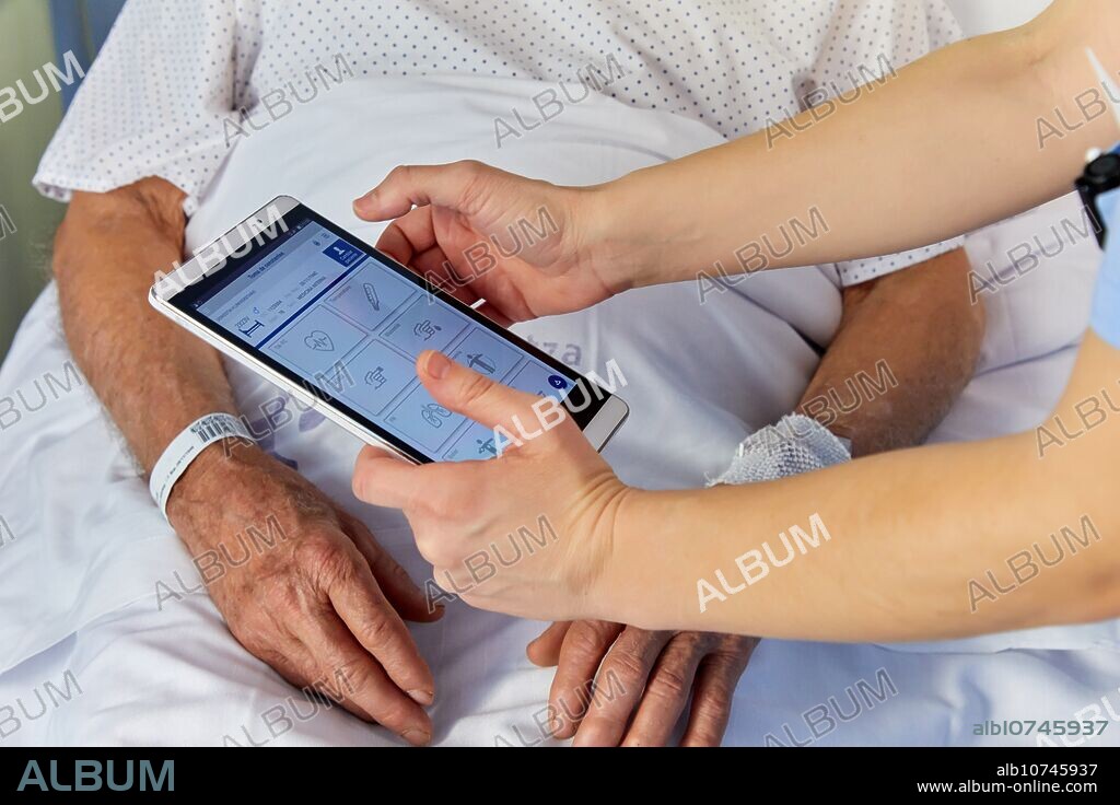 Nurse reading with the tablet the identification bracelet of a patient, hospital room, Hospital Donostia, San Sebastian, Gipuzkoa, Basque Country, Spain.