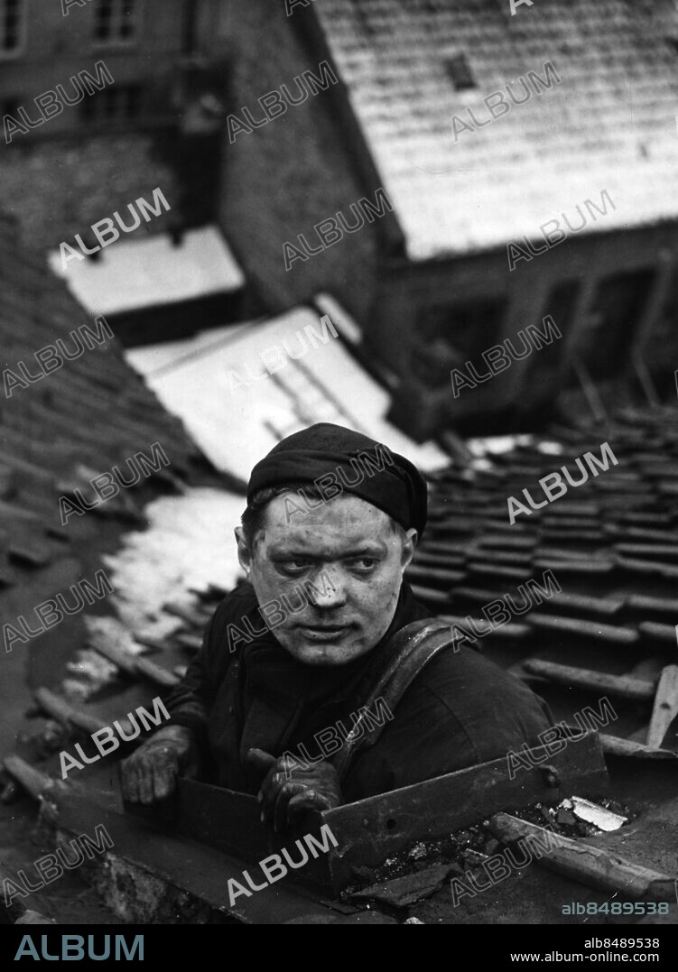 Sotare verkmästare Bengt Tilly tittar utpå tak av tegelpannon genom taklucka lucka i Malmö 1956. Foto: Sydsvenskan / IBL Bildbyrå. *** Local Caption *** A E Chimney sweep, Malmoe, Sweden 1956.