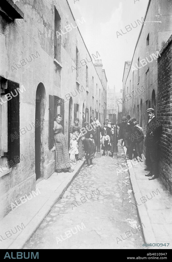 Little Collingwood Street, Bethnal Green, London, 1900s. Residents of the street pose for the photographer. Two of the boys in the front of the picture are barefoot. A little girl stands on the left, with a dog sitting in the begging position. Galt came to London in 1890 to work as a missionary for the London City Mission. In the early 1900s he took a series of photographs, mainly of the East End, which he had made into lantern slides to illustrate lectures publicising the work of the Mission. Galt sought to show that though there was great poverty in the East End, the people were not sub-human, as was popularly imagined by the middle-classes, but ordinary folk trying to do their best under difficult circumstances.