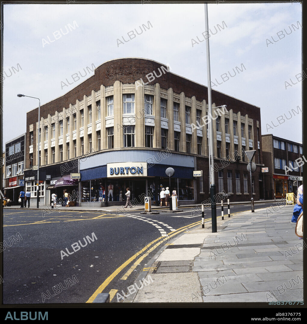 NICHOLAS ANTHONY JOHN PHILPOT. Burton, 127-133 High Street, Hornchurch, Havering, Greater London Authority, 1970s-1990s. The curved elevation of the Burton store on the corner of High Street and North Street, with the adjoining shops on either side. Foundation stones were laid at the site by members of the Burton family in 1939. The shop units in the building were occupied by businesses including the Post Office, Dollond and Aitchison Opticians, Dorothy Perkins, Douglas Estate Agents, and Boots.