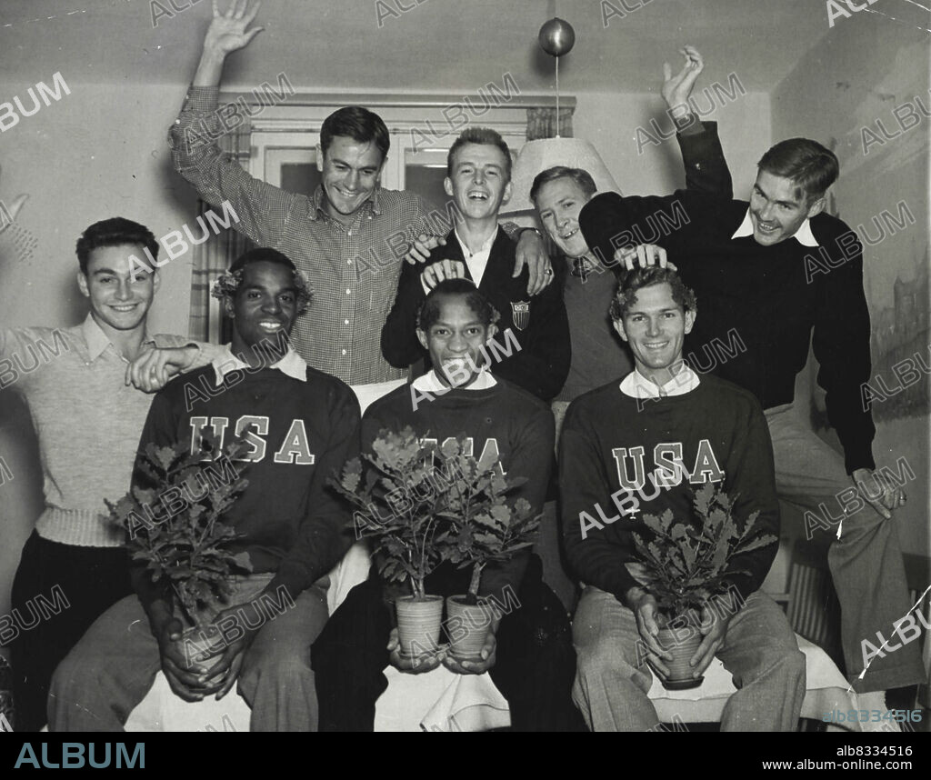 Trio Wins Firsts For AmericaLeft to right: Cornelius Johnson, Los Angeles, Olympic high jump record breaker, Jesse Owens, Cleveland, 100 meter, 200 meter and broad jump winner, and Glenn Hardin, Greenwood, Miss., 400-meter hurdle victor, are shown at their Olympic village quarters as they received congratulations from their American Olympic teammates as the first three Americans to win firsts in the Olympics here. In the back row, left to right are: Marty Glickman, Brooklyn, Relay man; Gene Venzke, Pottstown, PA., 1,500 meter entrant; Albert J. Mangin, Lowell, Mass., 5000 meter walker; Foy Draper, Whittier, Calif., member of the 400-meter relay team; and Forrest G. Towns, Augusta, GA., 100-meter hurdle winner. August 08, 1936. (Photo by Associated Press Photo).
