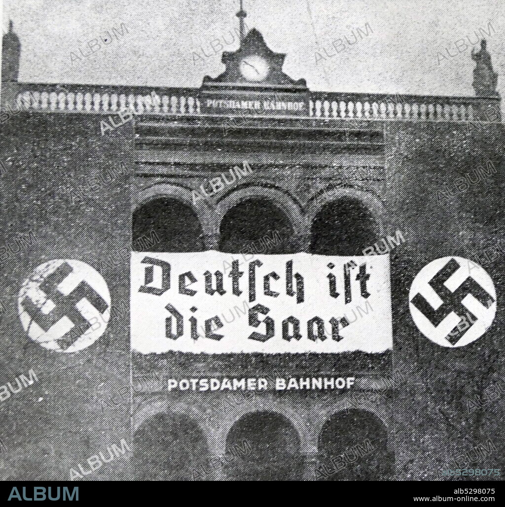 Black and white photo of the aftermath of the Saar Plebiscite, 13 January 1935; a sign with Nazi symbols celebrating the annexation of Saar.
