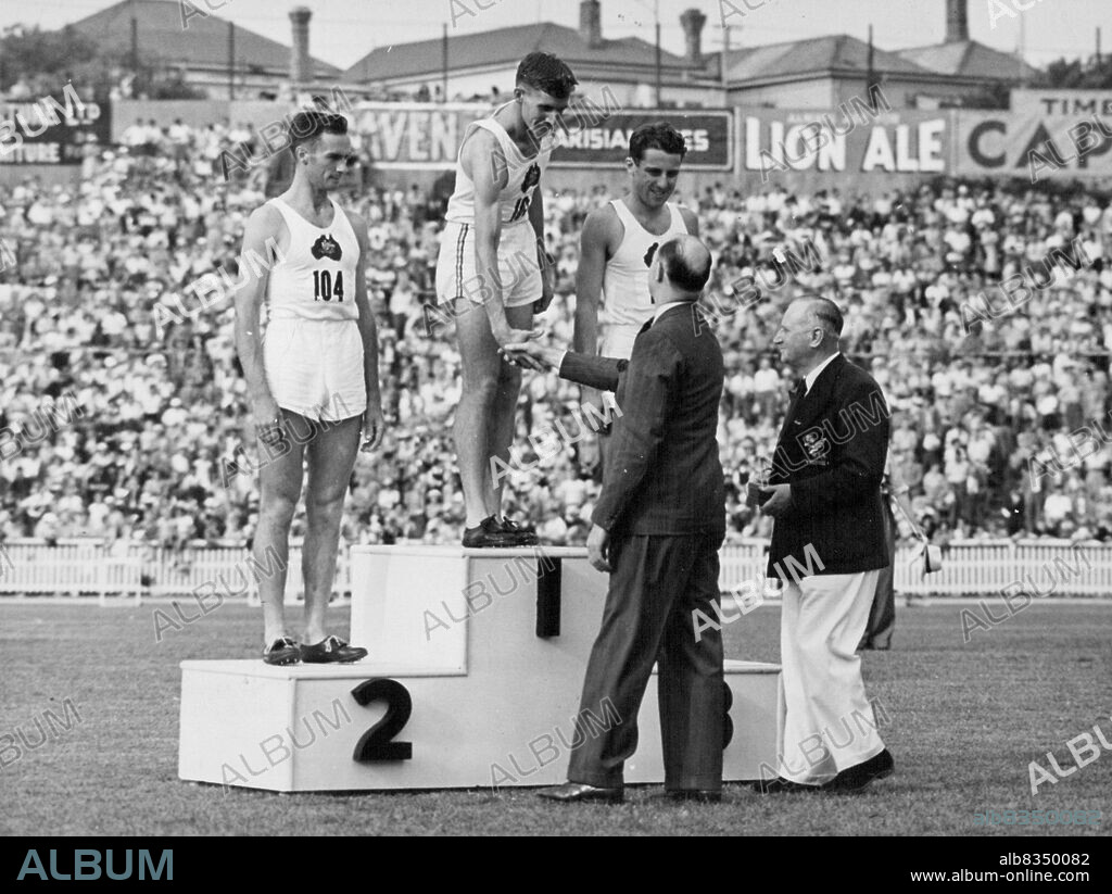 British Empire Games 1950. Empire Games Athletics at Eden Park, Feb. 9th. Third day.Australia takes first, second, and third in the hop, step, and jump, Mr. A. E. Porritt presents medallions to B. Oliver, first , L. A. McKeand, second, and I. J. Polmear, third. February 16, 1950.