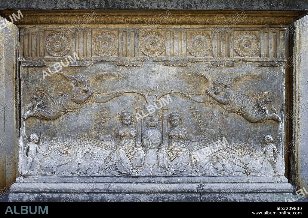 Detalle de uno de los bajorrelieves de los zócalos de las columnas exteriores de la portada del Palacio de Carlos V, en La Alhambra. Representación del triunfo de la Paz en las figuras de dos mujeres sentadas sobre armas y objetos bélicos. En el centro sostienen las columnas de Hércules y la tierra. Dos geniecillos de la Paz queman las armas. Su significado es que llega la paz y prosperidad al Reino de Granada y a toda España gracias a las victorias de Carlos V. Granada. Andalucía. España.