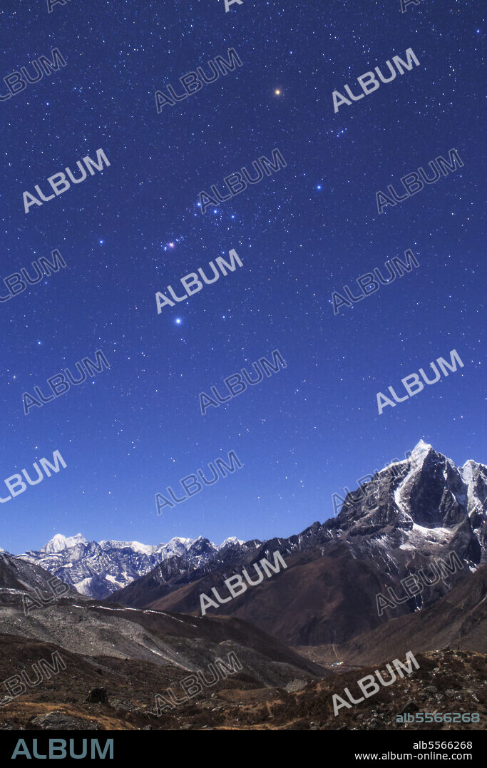 The famous constellation Orion appears over the moonlit landscape of the Himalayas as seen from the Sagarmatha National Park of Nepal.