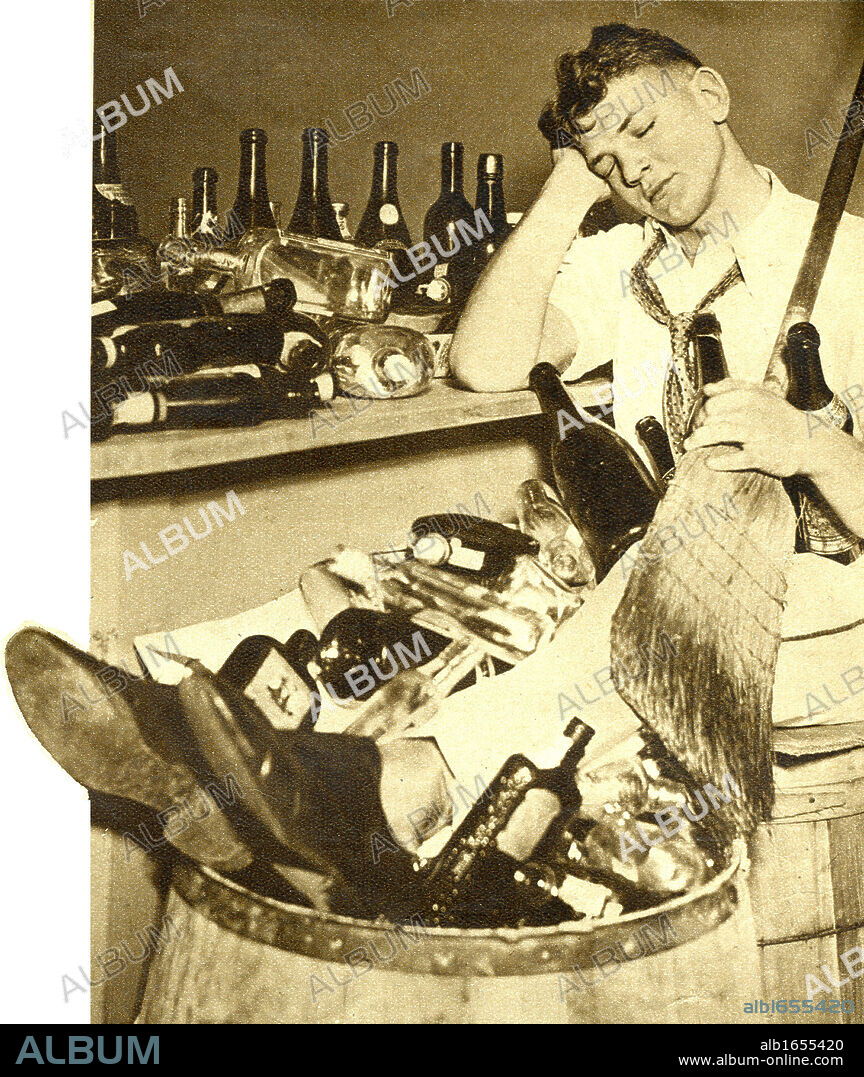 Repeal of Prohibition, 1933. American barman exhausted by clearing up the empty bottles after the celebration of the laws prohibiting the sale of alcohol.