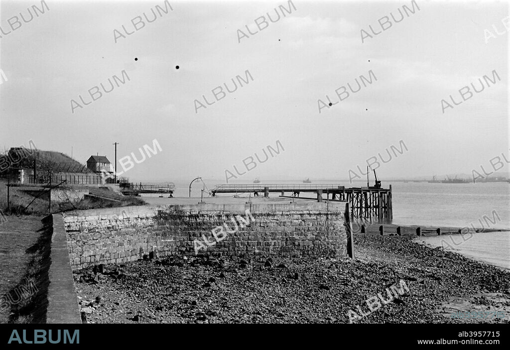 The quay outside the water gate of Tilbury Fort, Essex, c1945-c1965, looking along the south-east curtain of the Fort. The Fort was designed in the 17th century and partly remodelled in the 1860s. Note the World War II signal station and that the wooden jetty is damaged.