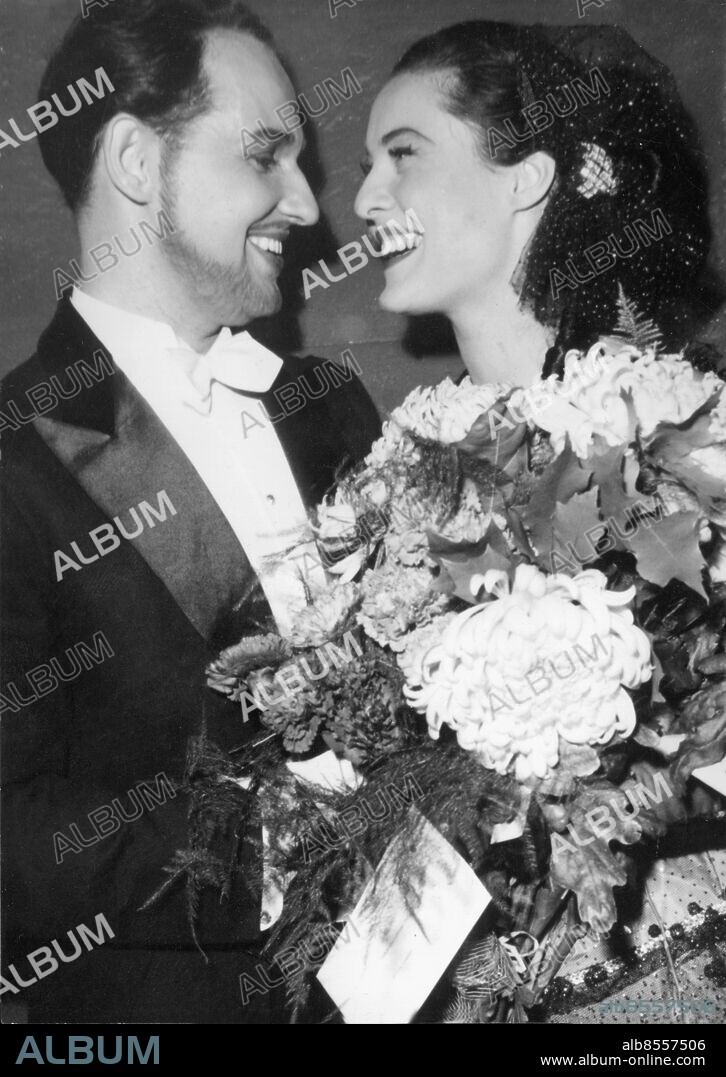 Orig. bildtext... GLADA ÄNKAN PÅ MALMÖ STADSTEATER. Malmö Stadsteater jubilerar i år och som jubileumsprogram har stadsteatern satt upp Glada Änkan med Ingmar Bergman som debuterande oprettregissör. Per Grunden och Gaby Stenberg spelade i huvudrollerna och de båda ses här med famnen full av blommor och glada leenden. 1-10-54 Anm. Malmö Stadsteater firade 10-årsjubileum 1954. P Grundén, 1922-2011, svensk operasångare (tenor) och skådespelare. G Stenberg, 1923-2011, svensk skådespelerska och sångerska. Glada änkan, operett av Franz Lehár, uruppförd 1905 i Wien. Skådespelare Ögonkontakt Profiler Buketter Smoking Fluga Leenden Hårnät Smink Skägg Mustascher CD678 persons: GABY STENBERG;PER UNDÉN sites: MALMÖ;SVERIGE.