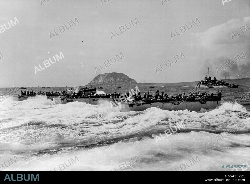 Invasion of ***** Gets Under ***** filled with tense marines, landing craft head for the crashes of Iwo Jima, February 19 (Iwo Jima, as Suribachi, extinct volcano of the Island. Looms up in the background. The Marines now control the volcano after a daring frontal assault. February 25, 1945. (Photo by Associated Press Photo).