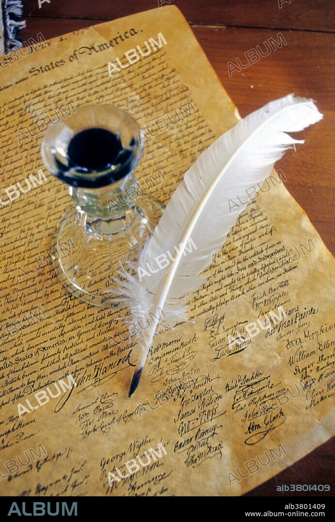 Feather ink pen and inkwell rest on copy of the United States Declaration of Independence.