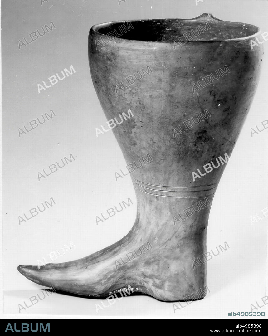 A vase of brown to gray shiny clay in the shape of a boot, annular ear, thin-walled. engraved decoration. The object is polished. The imprinted imitation of boot seams and of the closed closure is strongly reminiscent of Urart examples, tableware, ceremonial object, pottery, H 16.8 cm, D 10.6 cm, Iron Age 800-600 BC, Turkey.