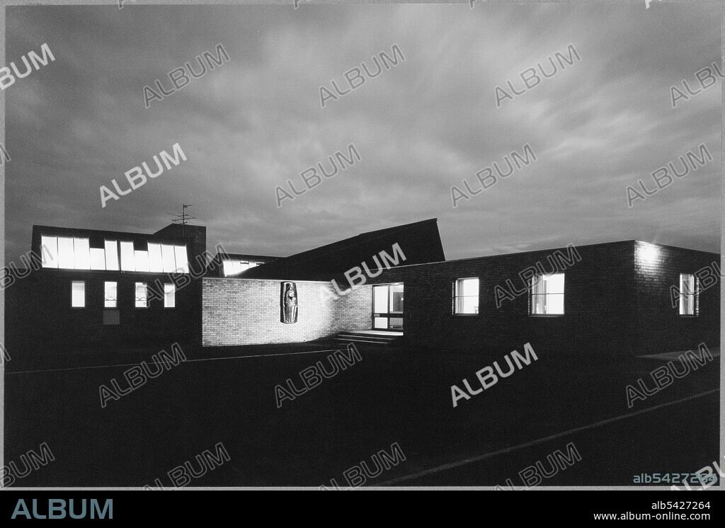 St. Bede's Catholic Primary School, Hampshire Place, Sunderland, 1968-1975. General, exterior view of the entrance area to St. Bede's Catholic Primary School, Washington, Sunderland, taken at night, showing illuminated interiors and a suspended bas relief of St. Bede. A handwritten caption on the reverse of the image reads, "C.C.S. 331A." It is unclear who, or what, this relates to, but it is perhaps another photographers and their own image reference code.