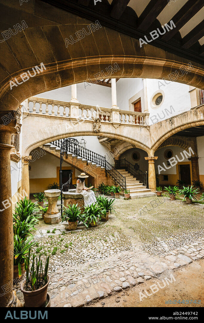 woman in white suit enjoying Can Oleza courtyard(Historic-Artistic Monument) (17th century), Historic Center, Palma, Mallorca, Spain.