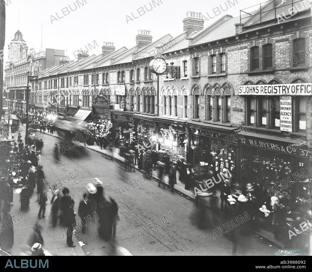 Busy street scene, St John's Road, Clapham Junction, London, 1912. People crowding the pavements outside shop windows.