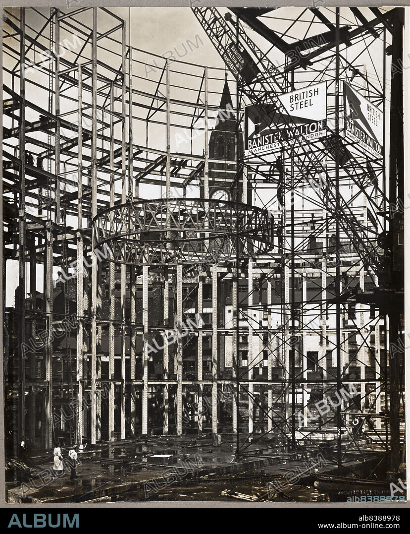 STEWART BALE LIMITED. Central Public Library, St Peter's Square, Manchester, 1930 - 1934. The upper dome ring being hoisted into position during the construction of the Central Public Library. The Central Public Library was designed by E Vincent Harris. The steel frames were manufactured by Banister, Walton and Co Ltd. The image also shows a temporary erection tower (with posters attached), and workmen climbing an adjoining ladder. The time of the photograph, shown on the Town Hall clock in the background, is 1.35pm. The upper dome ring is shown halfway to its position.