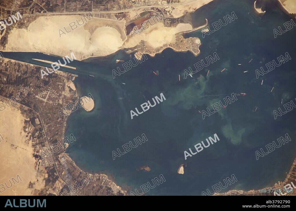The Great Bitter Lake is one of several lakes located along the Suez Canal, which connects the eastern Mediterranean and Red Seas. As the canal is built only to allow ships to travel in a single lane, the Great Bitter Lake is a location where ships can change their position in line (like the passing lane on the highway) before proceeding to either Port Said to the north, or the port of Suez to the south. The lake also provides an intermediate harbor for ships traversing the Canal,a journey that typically takes 14 hours end to end. Several ships, some under power and some anchored, are visible at image right.