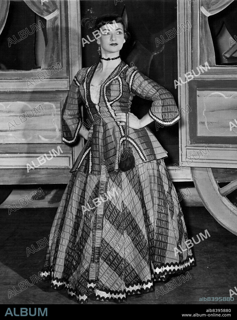 Provocative girl, Shirley Murphy, of Maroubra, Sydney, wears a gaudy, green gown and a red hat with a feather. She has a 32-23-34 figure. In real life she likes basketball. July 16, 1955.