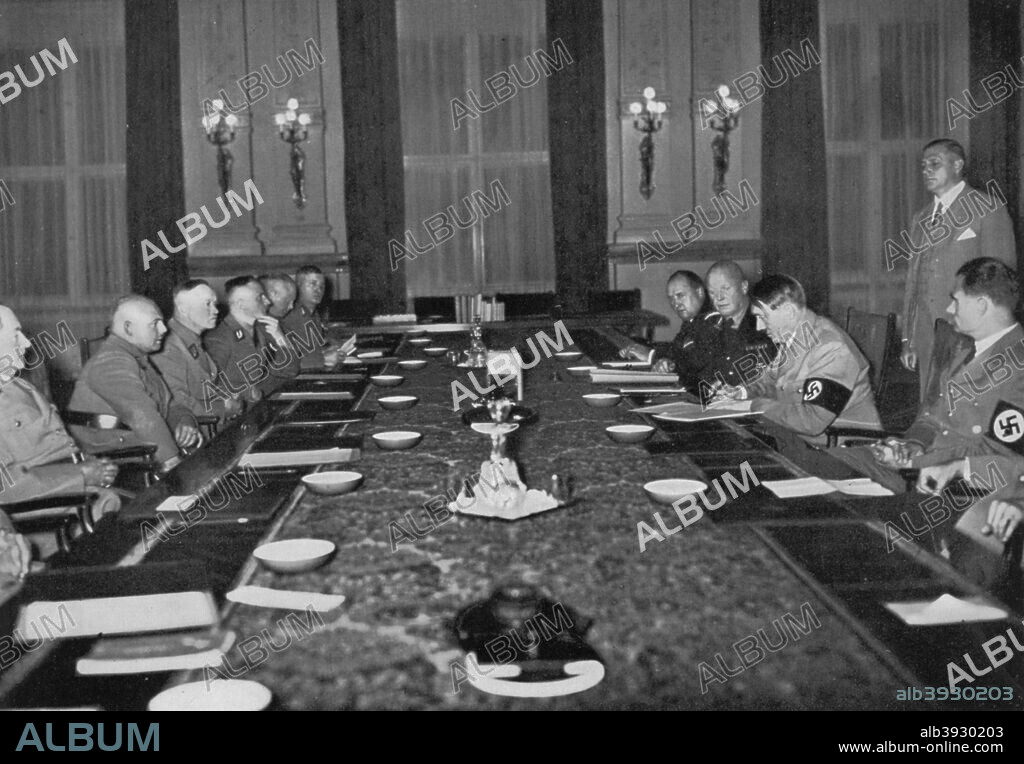 Meeting of the Reichsstatthalter at the Reich Chancellery, Berlin, Germany, 1936. The Reichsstatthalter (state governors) meeting under the presidency of Nazi leader Adolf Hitler (1889-1945). Deputy Führer Rudolf Hess (1894-1987) is sitting on Hitler's left. A print from Adolf Hitler. Bilder aus dem Leben des Führers, Hamburg: Cigaretten/Bilderdienst Hamburg/Bahrenfeld, 1936.