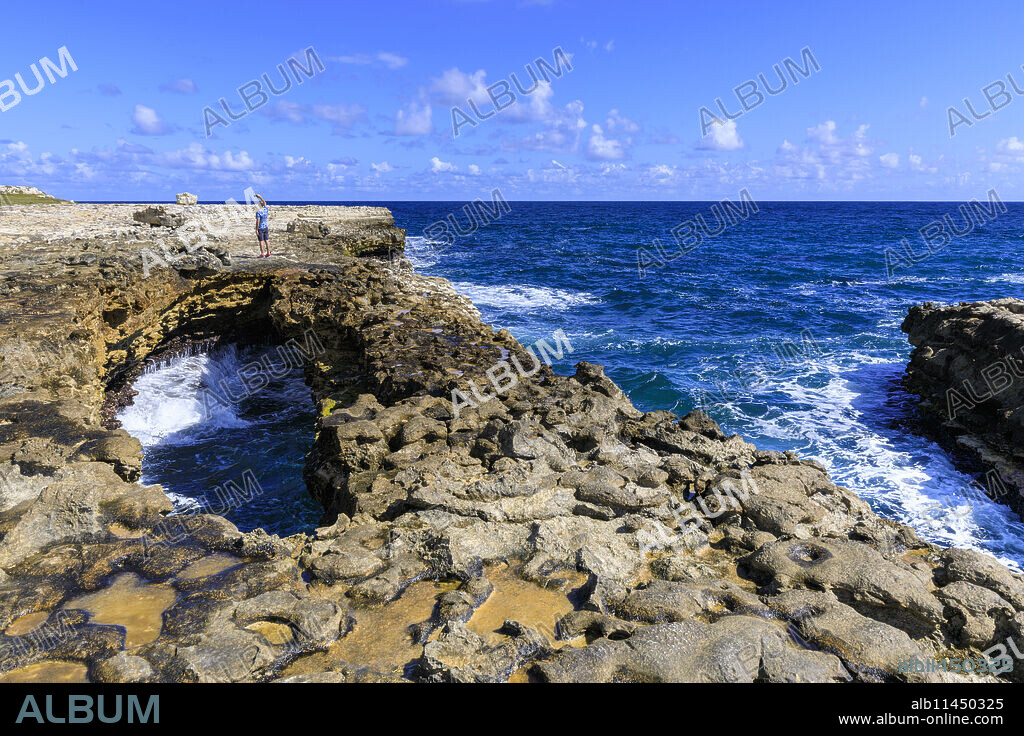 Devil's Bridge, limestone rock formation and arch, tourist takes selfie, Antigua, Antigua and Barbuda, Leeward Islands, West Indies, Caribbean, Central America.
