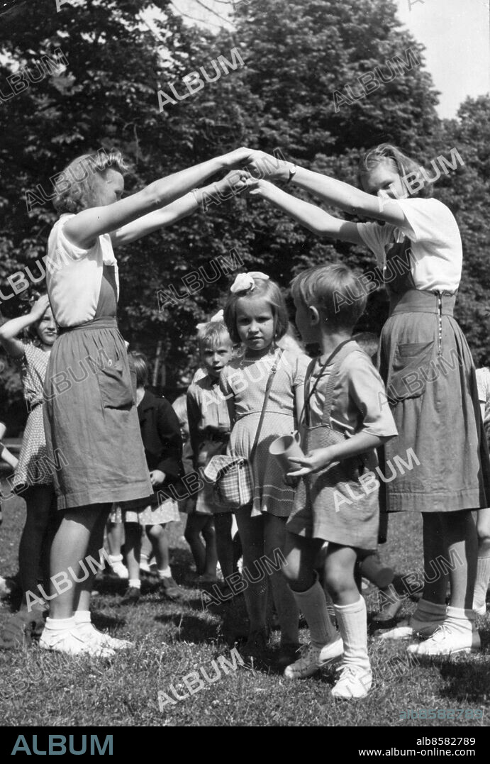 Stockholm 1946-07-04. Parklek. Bro bro och breja leker några småttingar från Fredhäll med hjälp av sina lektanter, som bildar bron. På onsdagensmorgonen gjorde parkleken sin första utflykt till Haga. Det var barn från Fredhällsparken, Kronobergsparken och Vasaparken som premiärlekte för året på ängen framför Koppartälten.. Foto: DN / TT / Kod: 192. ** SvD OUT **.