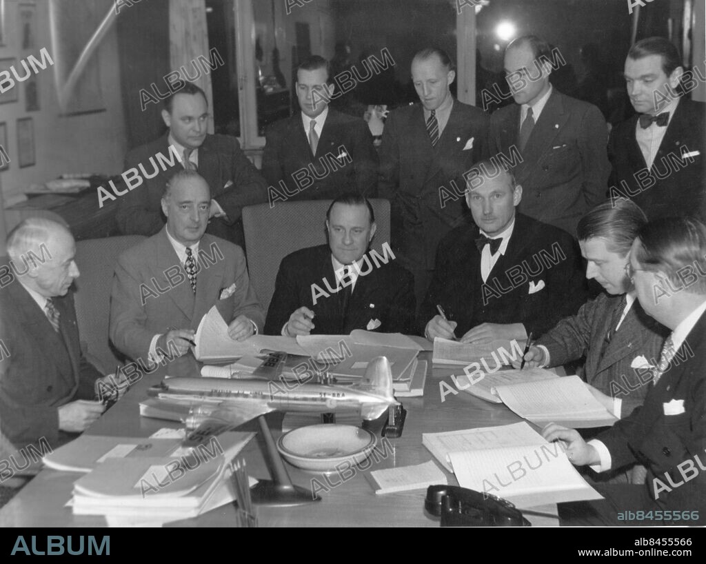 Orig. bildtext... DOUGLASPLAN FÖR 50 MILJ.KR TILL SKANDINAVIEN. Kl. 17.00 på fredags e.m. undertecknade de skandinaviska flygboloagen ABA, DDL och DNL samt SILA ett 50-milj.kr:skontrakt med Douglas Aircraft Comp.:s förs.ch. gen. Victor E. Bertrandias omfattande leverans av 17 st. flygplan av typ DC 6. Stående fr.v.: Adv. Erik Norman, ABA, inköpsch. U. Simonsen, DDL, öv. Johann Christie, DNL, ing. H.W.Ree, DNL, öv.ing. Svend Hansen, DDL. Sittande fr.v.: dir. Karl Lignell, ABA, dir. Carl Florman, ABA, gen. Victor Bertrandias, Douglas, dir. Marcus Wallenberg, SILA, dir Per A. Norlin, SILA, och öv. ing. K.H. Larsson, ABA. Anm. Kontrakt persons: VICTOR BERTRANDIAS;SVEND HANSEN;PER A NORLIN;MARCUS WALLENBERG;KARL LIGNELL;JOHANN CHRISTIE;CARL FLORMAN sites: SVERIGE.
