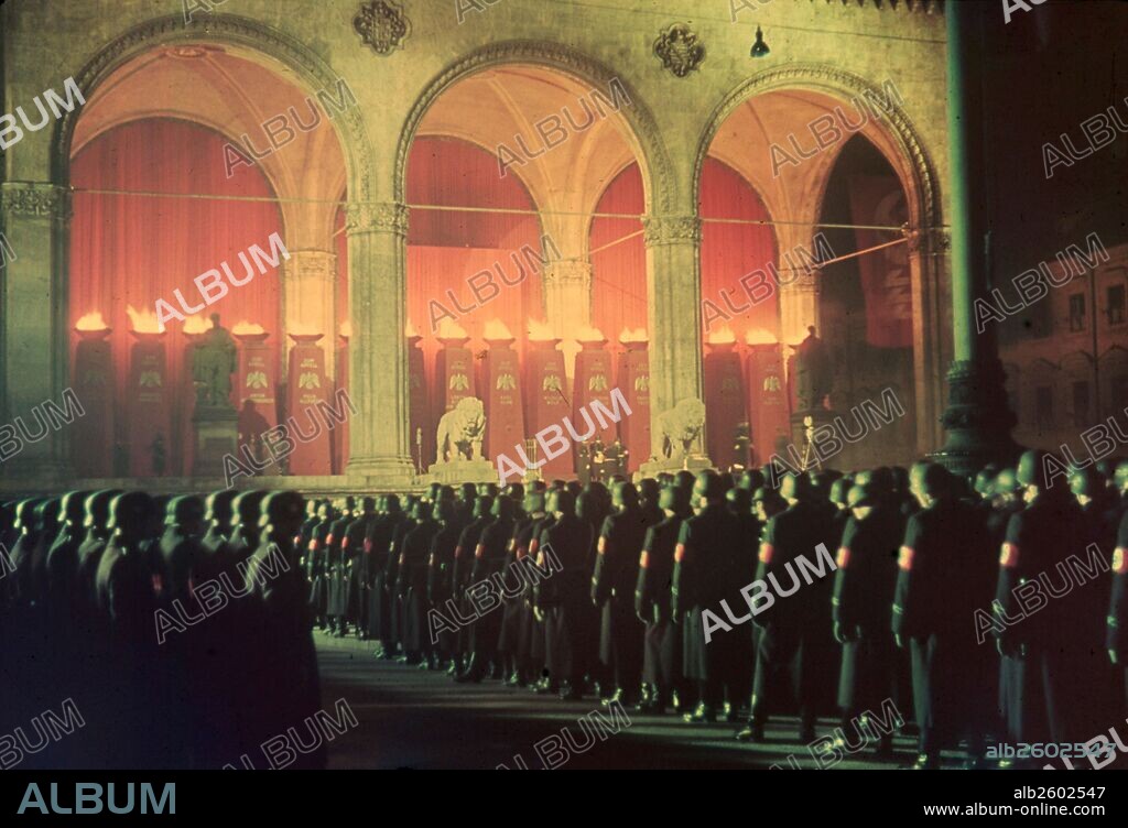 Colour image shows the gathering of the annual midnight swearing-in of Nazi SS troops. Every year the Nazi troops would have to swear an oath of loyalty. The oath read - “I vow to you, Adolf Hitler, as Führer and chancellor of the German Reich, loyalty and bravery. I vow to you and to the leaders that you set for me, absolute allegiance until death. So help me God.” Feldherrnhalle, Munich 1938.