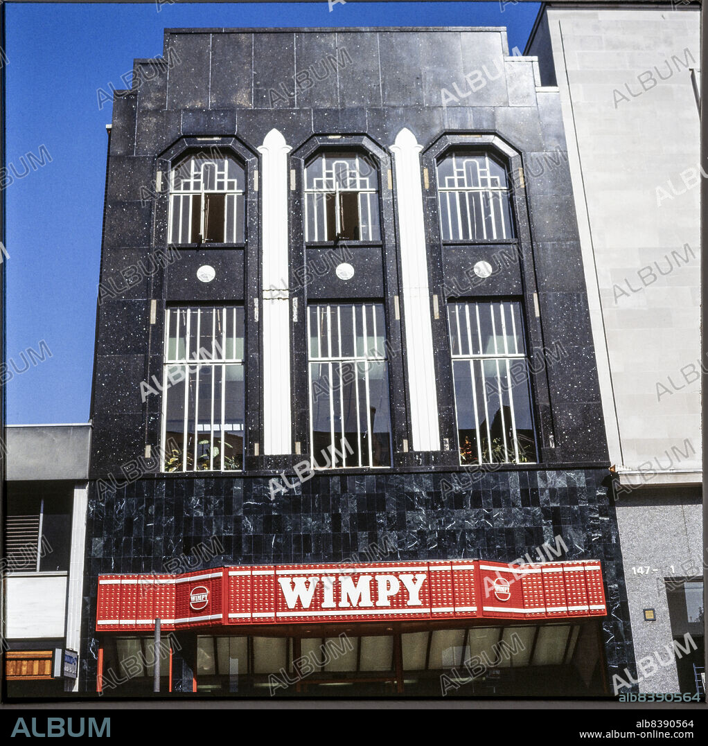 NICHOLAS ANTHONY JOHN PHILPOT. 145 High Street, Slough, 1980s-1990s. The front of the Wimpy restaurant at 145 High Street, a former Burton store with a polished granite facade. The building was previously numbered 83-85 High Street. Historic mapping shows that it was renumbered as no. 145 at some point between 1956 and 1967. The facade is probably one of several granite facades to feature on Burton stores, including at Reading, Kingston upon Hull and Bournemouth. It was replaced or covered with a brick facade by the early 21st century, at which time the premises were occupied by a branch of Halifax bank.