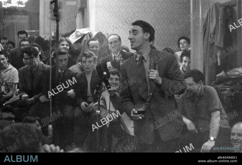 Dominic Behan singing at a folk session, Enterprise Public House, Long Acre, London, c1959. Folk club session during the folk revival of the late 1950s and early 1960s. In the background are folk musicians Peggy Seeger, Ewan MacColl and AL Lloyd.