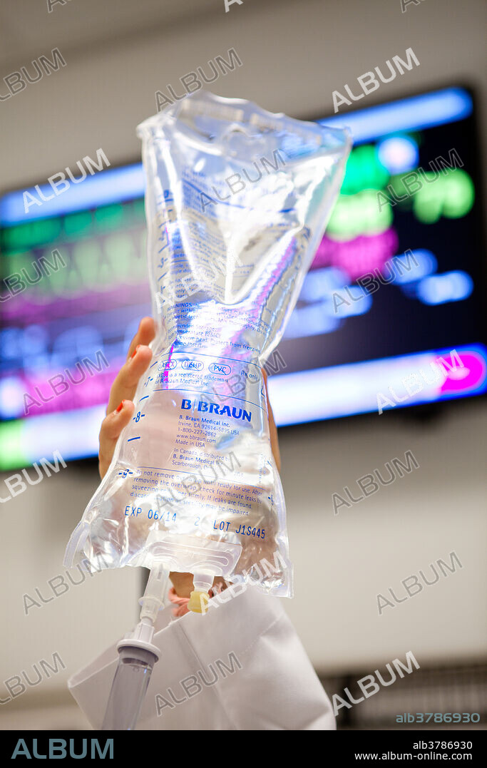 Intravenous (IV) drip bag. Hand raising an intravenous (IV) drip bag containing .9%, sodium chloride solution and plastic tubing. When in use, a tube carries the solution into the bloodstream, usually through veins in the forearm. Saline and glucose are used to maintain body fluids in patients who are unable to eat or drink. An intravenous infusion, or drip, may also be used to provide nutrients, to administer certain drugs, or to replace lost blood and plasma. The rate at which the saline enters the circulation is controlled by an adjustable valve.