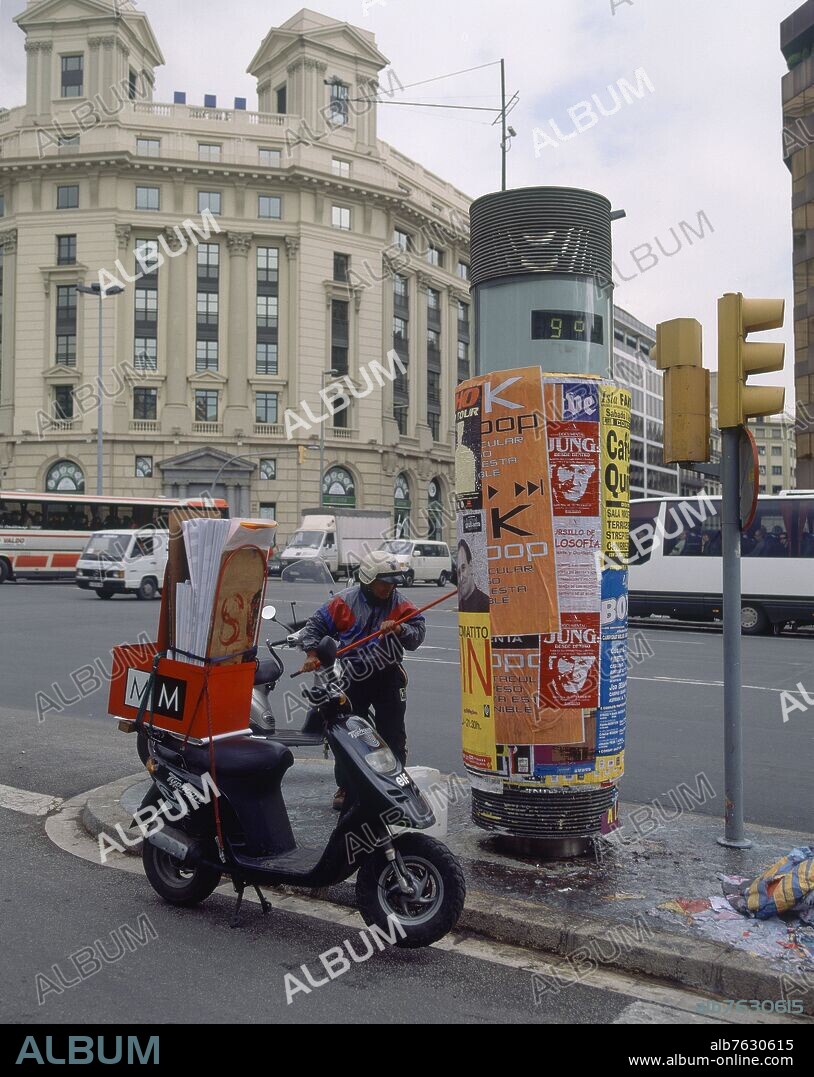 PEGANDO CARTELES EN EL MOBILIARIO URBANO DEL PASEO DE GRACIA.