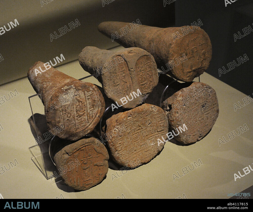 Antiguo Egipto. Conos funerarios realizados en arcilla. En la base mostraban inscritos el nombre y los títulos del difunto. Empotrados en hileras en las fachadas exteriores de las tumbas, tan solo era visible la inscripción, de tal forma que constituían una marca de propiedad de las tumbas de la Dinastía XVIII de la región de Tebas. De izquierda a derecha, y de arriba a abajo: cono de Totemhab (escriba de la ciudad meridional), cono de Tchai (con la fórmula de ofrendas), cono de Senhotep (escriba de la Casa de Vida), cono de Amenemenka (segundo profeta de Menkheperra, y de su esposa, Merytra, cantora de Amón) y conos de Djeho (hijo de Ankhor, hijo del noble, el príncipe, el gran jefe de los Mashauesh, el jefe de los profetas de Banebdjed, Djeho. Su madre era la dama Shepensopdet). Museo Arqueológico Nacional. Madrid. España.